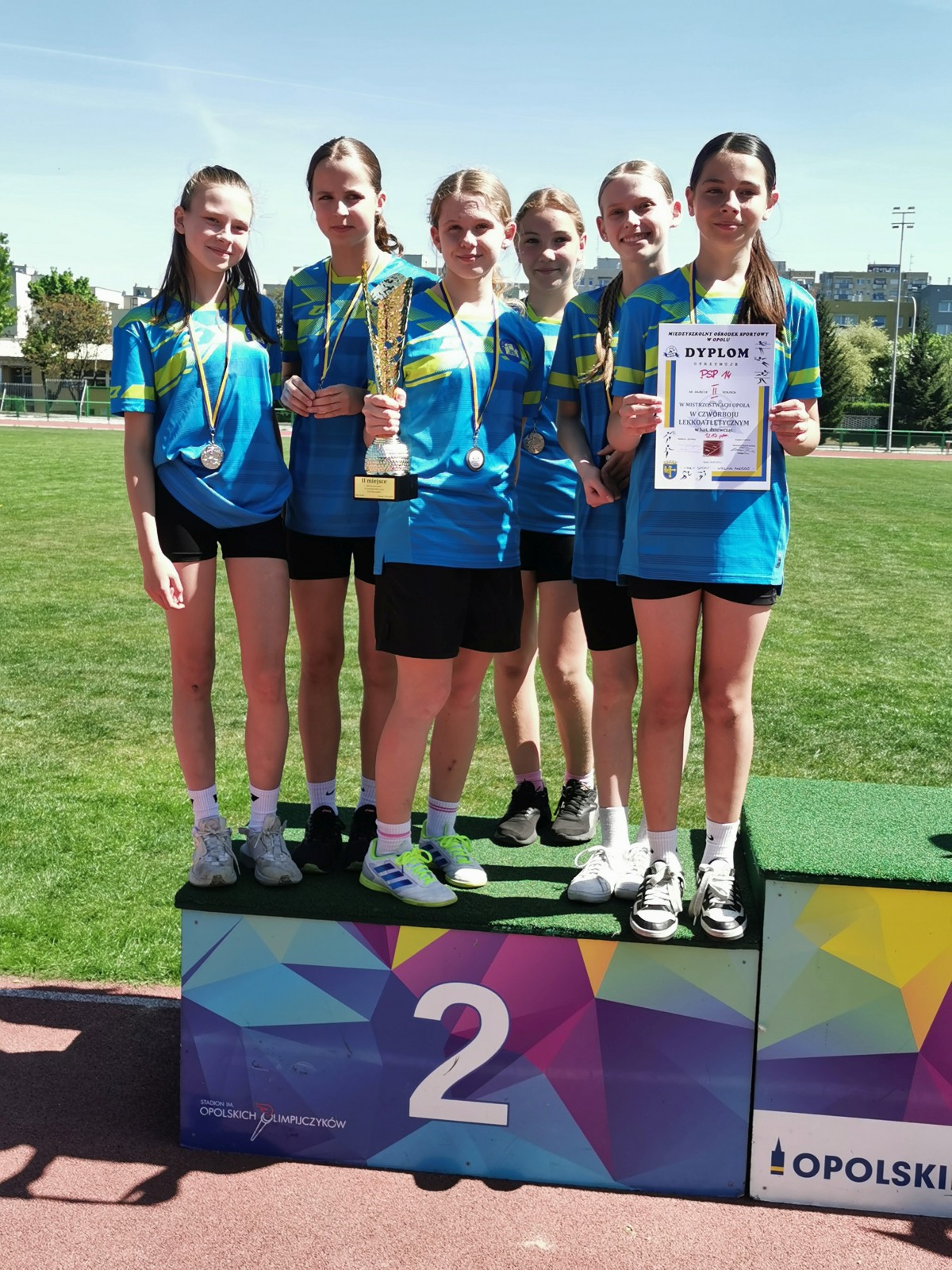 Dziewczęta na podium z medalami, pucharem i dyplomami