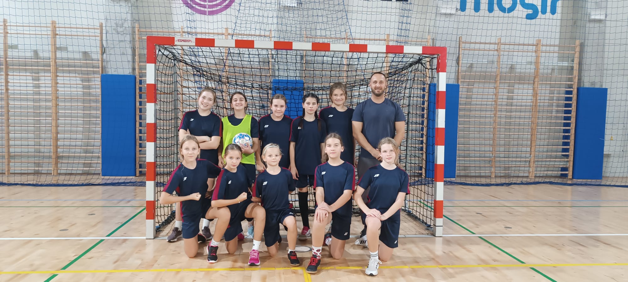 Futsal żeński - zdjęcie grupowe zawodniczek z trenerem na tle bramki