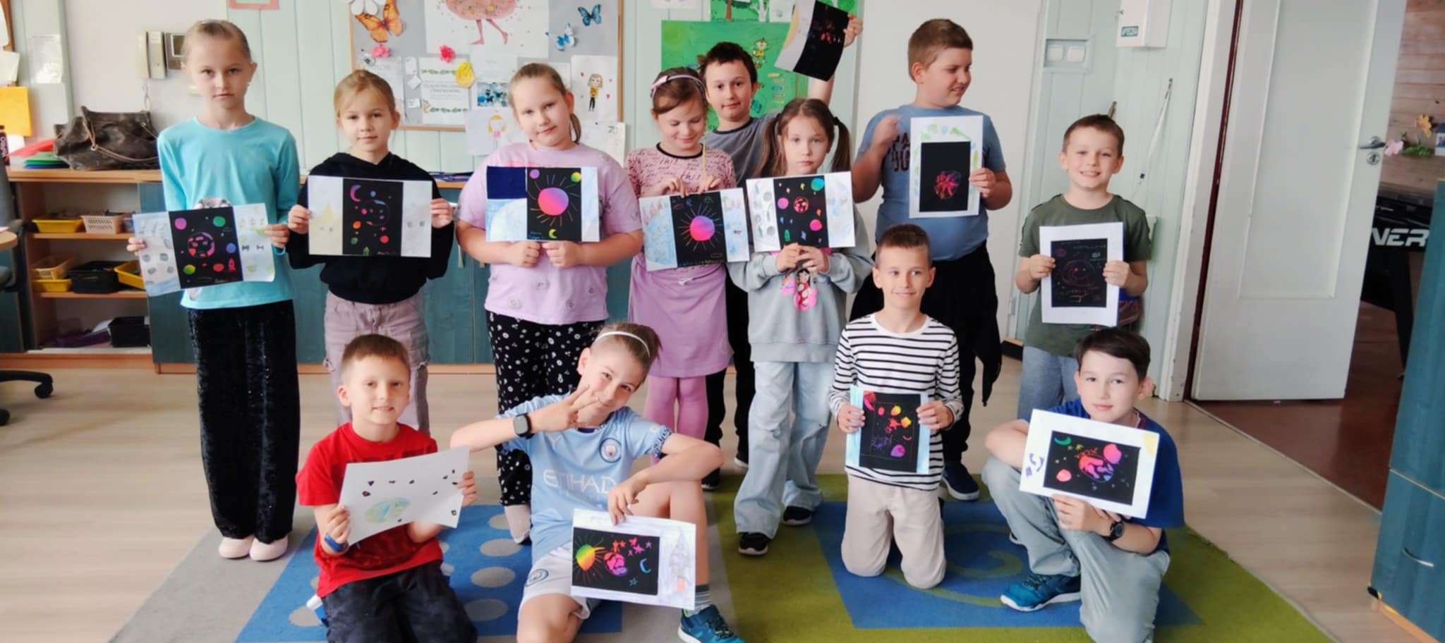 Zdjęcie grupowe uczniów z pracami plastycznymi w rękach